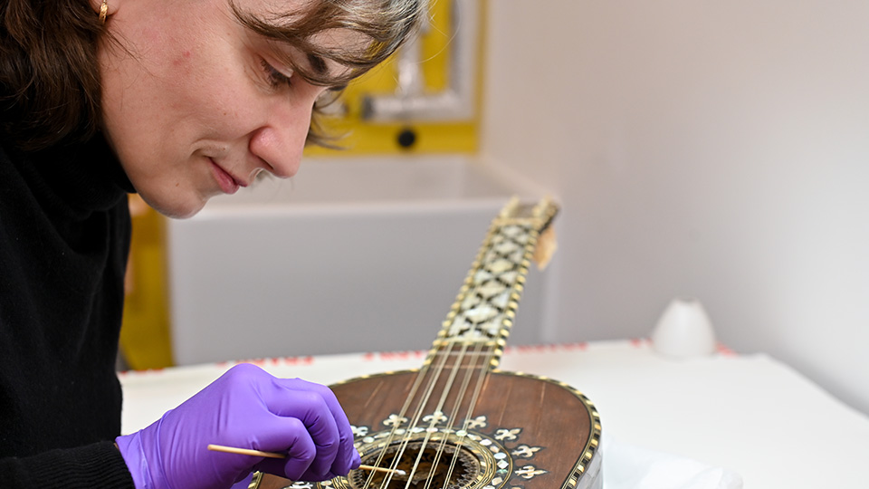 A person using a small tool to clean a guitar in the Wolfson Centre